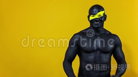 男人选择复制空间。 健美运动员，有黄色的面部艺术和黑色的身体油漆。 他的彩色肖像和