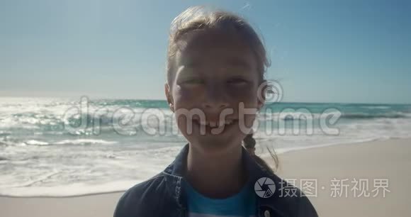 前景女孩看着海滩上的摄像机