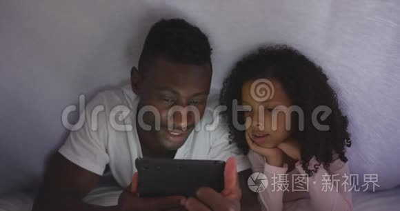 非裔美国人父女在床上看电话视频