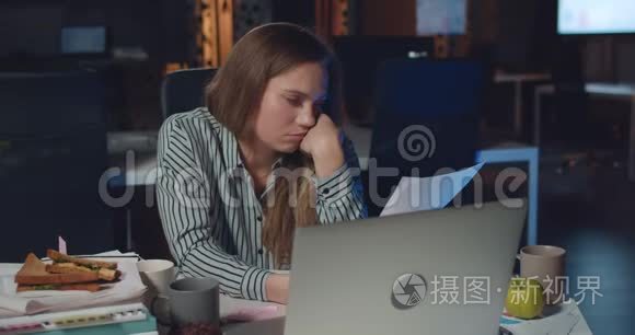 年轻的女经理看着疲惫的工作，睡在手边。 累了的女上班族一边看文件
