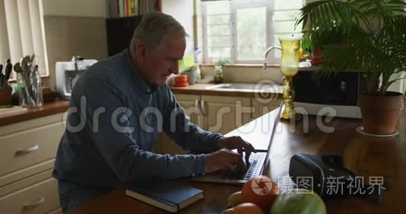 在家使用笔记本电脑和手机的老人