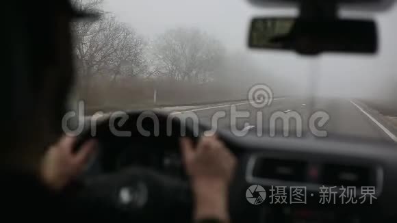 男司机在雾蒙蒙的路上开车.. 从车内铺设现代道路。