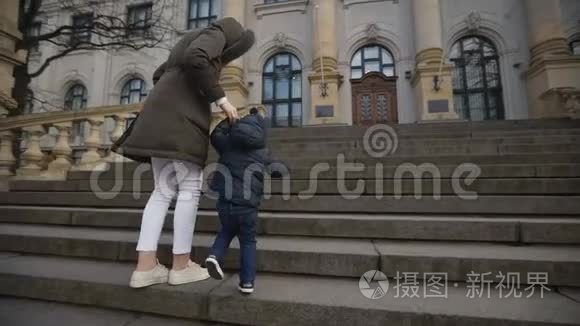 小男孩在国家艺术博物馆的楼梯上，妈妈牵着他的手。 慢动作