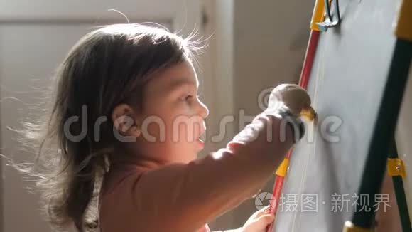 可爱的小女孩在粉笔板上用蜡笔画