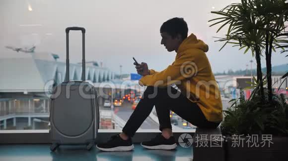 青年游客带行李在机场候机楼等候的剪影，旅客使用