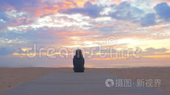 美丽的日落过海，女人坐在沙滩上