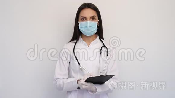 友好的女医生穿着白色的医用外套手套和防护面罩，把诊断写在客户卡上，