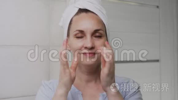 头上戴毛巾的女人涂了乳液或油，看着镜头