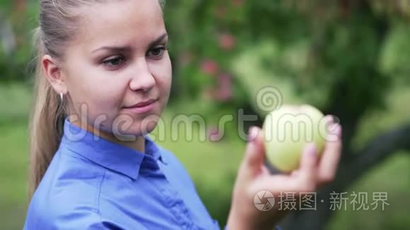 一个穿着蓝色衬衫的年轻女孩看着一个苹果
