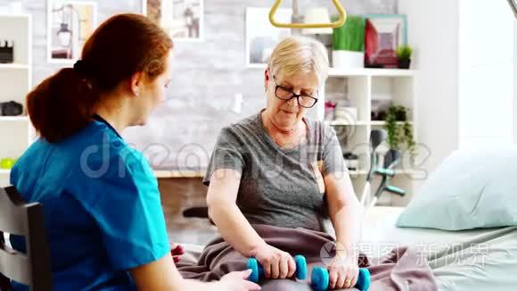 养老院的护士帮助一位老年妇女恢复肌肉力量