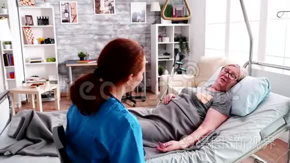 女性医护人员抱着躺在病床上的老妇人