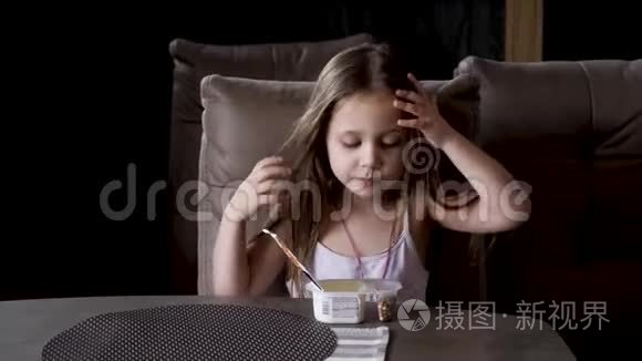 坐在桌子旁吃酸奶的小女孩。 儿童食品