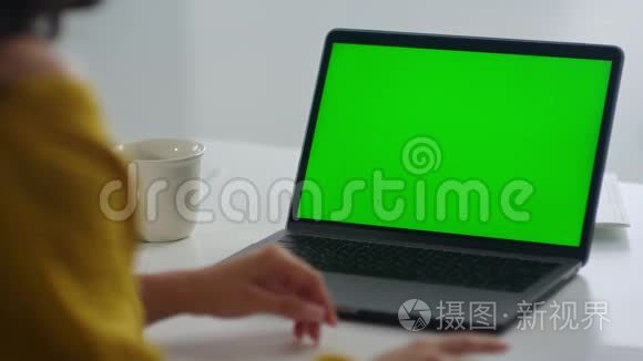 看不见的女人看着绿色屏幕笔记本电脑。 女孩用手势解释