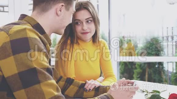 可爱的女孩坐在咖啡馆的桌子旁。 她正在和男朋友交流，男朋友给她看一些东西