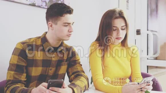 可爱的女孩坐在咖啡馆的桌子旁。 他在看他女朋友手机。 快关门。 复制空间。