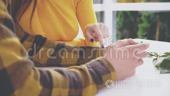 可爱的女孩坐在咖啡馆的桌子旁。 她正在和男朋友交流，男朋友给她看一些东西