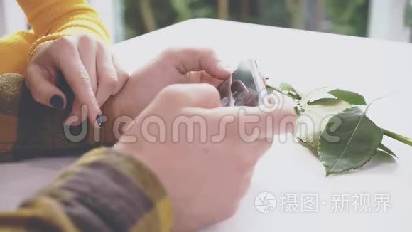 可爱的女孩坐在咖啡馆的桌子旁。 她正在和男朋友交流，男朋友给她看一些东西