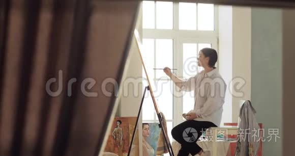 画家正在画架上画一幅画，坐在靠近窗户的地方，。