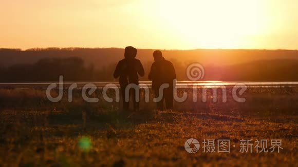 两个朋友夕阳西下往前走，探险旅行的概念，肩上背着一个背包