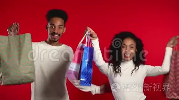 快乐的非洲夫妇，在购物后带着五颜六色的纸袋，与红色隔离