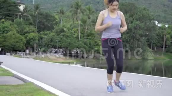 年轻健康的亚洲女人在公园晨跑时停下来系鞋带