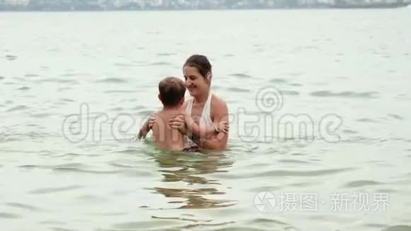4K镜头，快乐的微笑母亲和她的小儿子在海洋游泳时玩得开心和拥抱