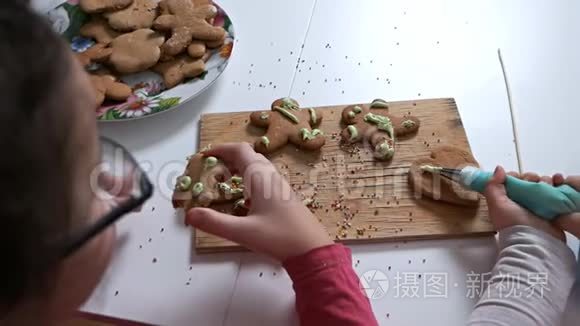 孩子们的手特写为节日装饰姜饼干。姜饼图案