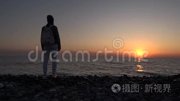 一个旅游女孩欣赏海滩上的日落。 浪漫的场景。 剪影