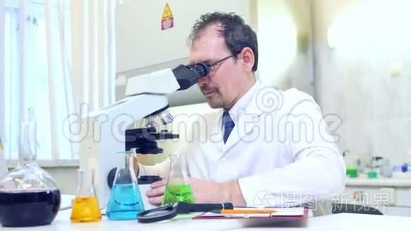 化学家疯了。 一个疯狂的科学家在一个科学实验室进行实验。 用显微镜进行研究。
