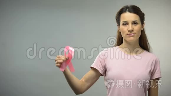 在镜头中展示粉红色丝带的女人，国际乳腺癌意识