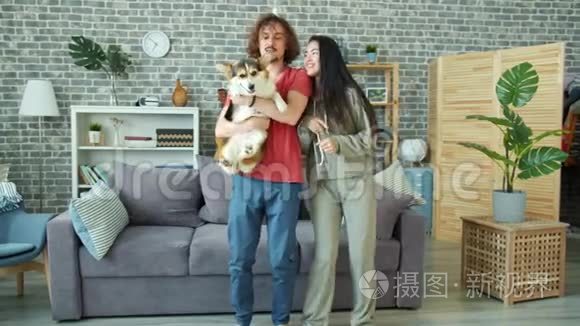 一对幸福的夫妇抱着威尔士科吉彭布罗克狗在家里跳舞