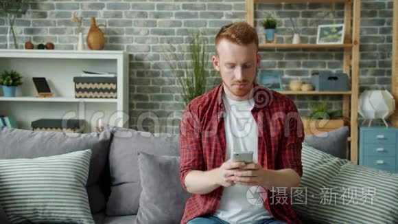 一个快乐的男人在家里用智能手机触摸屏幕，独自笑着休息