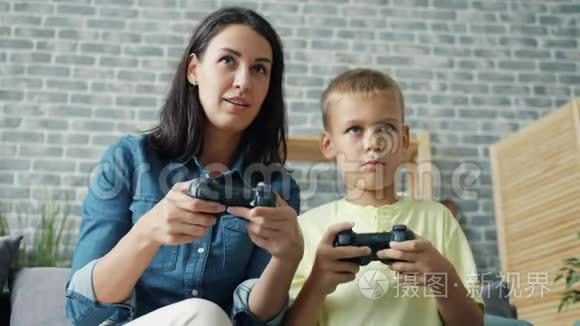 小男孩在玩电子游戏，有爱心的妈妈拿着操纵杆，按按钮