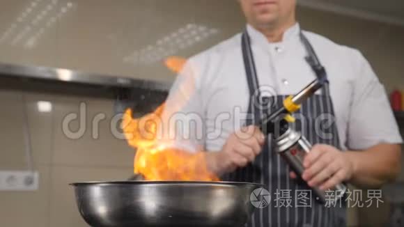 厨师在餐厅厨房做饭。 用火焰烹饪，从煎锅中升起火焰的慢动作镜头。 Hd