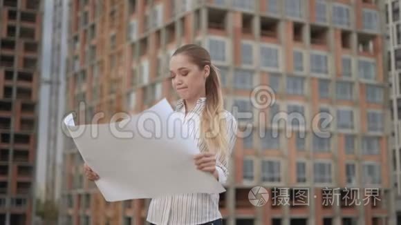 女建筑师将施工进度与蓝印笔记进行比较.. 女人在一幅大画的手中吞食。 4K