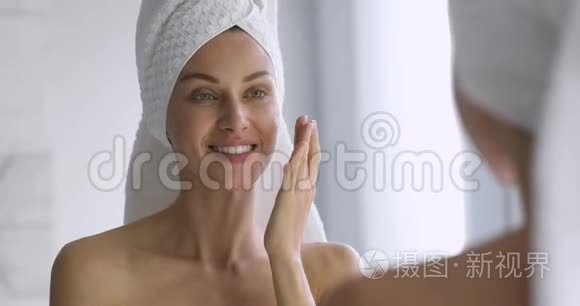 有趣的女人在脸上涂上护肤霜，照镜子