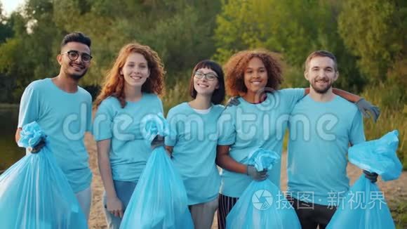 欢乐的朋友，环保活动人士，手里拿着垃圾袋，站在河岸上拥抱