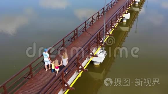 一家人沿着木桥走过湖面。 空中射击。
