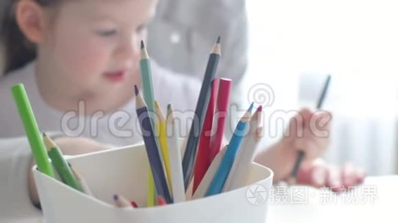 幸福的家庭，妈妈保姆教可爱的小女孩在桌子旁画画，妈妈帮小女儿学画画