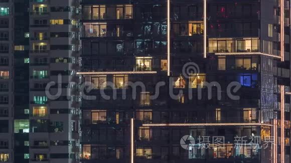 一排排发光的窗户，晚上公寓大楼里的人。