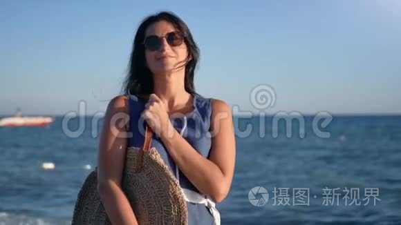 放松的旅行女性，戴太阳镜，在日落时在海景中拍照