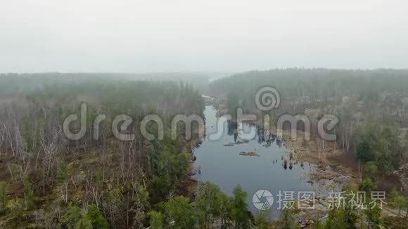 无人机沿海岸之间的池塘飞行，秋天的森林和雾蒙蒙的地平线。 加拿大马尼托巴省麦克吉利夫雷瀑布