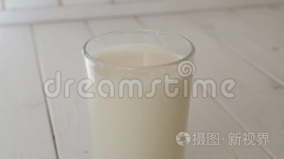 在轻木质的表面上，滴入满杯牛奶的奶液
