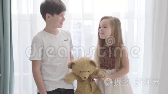 小白种人女孩和男孩抱着泰迪熊，互相看着，微笑着。 快乐的孩子花时间