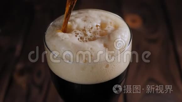 在木制背景下，一杯浓墨重彩的啤酒慢慢地倒在杯子里。