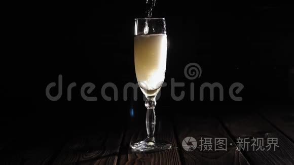 酒保的特写镜头将香槟倒入黑色背景的玻璃杯中。
