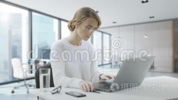 女人坐在办公桌前用笔记本电脑。 年轻的欧洲女商人正坐在办公室里工作