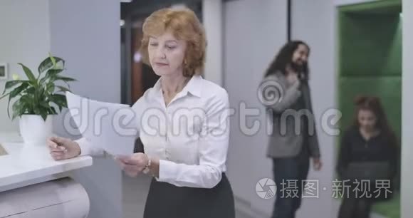 自信的中年白人妇女站在文件，回头看同事，摇头。 首席执行官画像
