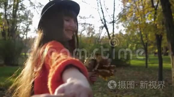 秋天公园里漂亮的女孩，戴帽子的年轻风趣的女人在周末的时候欢快地奔跑，牵着朋友的手