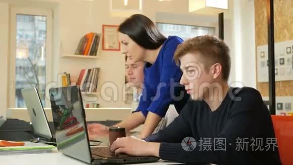 漂亮的女孩在办公室的笔记本电脑上咨询男人关于这个项目的情况。 它在屏幕上显示了你的手指